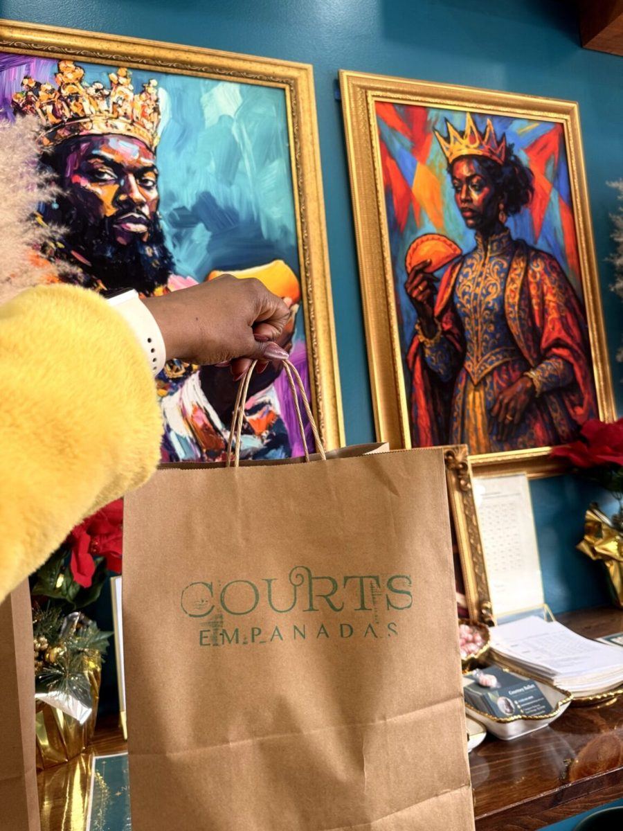 A Courts Empanadas takeout bag in front of the royal portraits