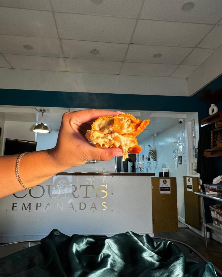 Peaches & Cream mini empanada held up inside Courts Empanadas